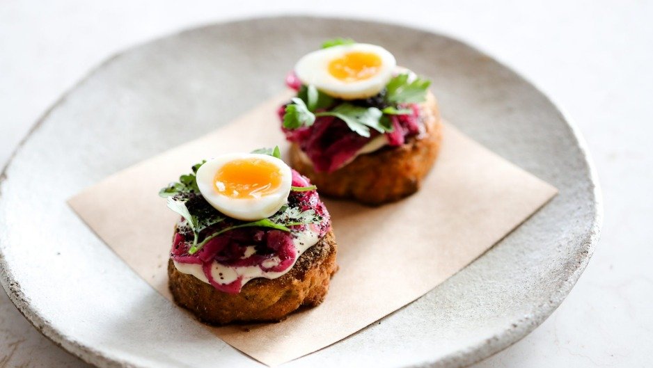 Delicious open-faced beet and egg sandwiches on a rustic ceramic plate, garnished with fresh greens.