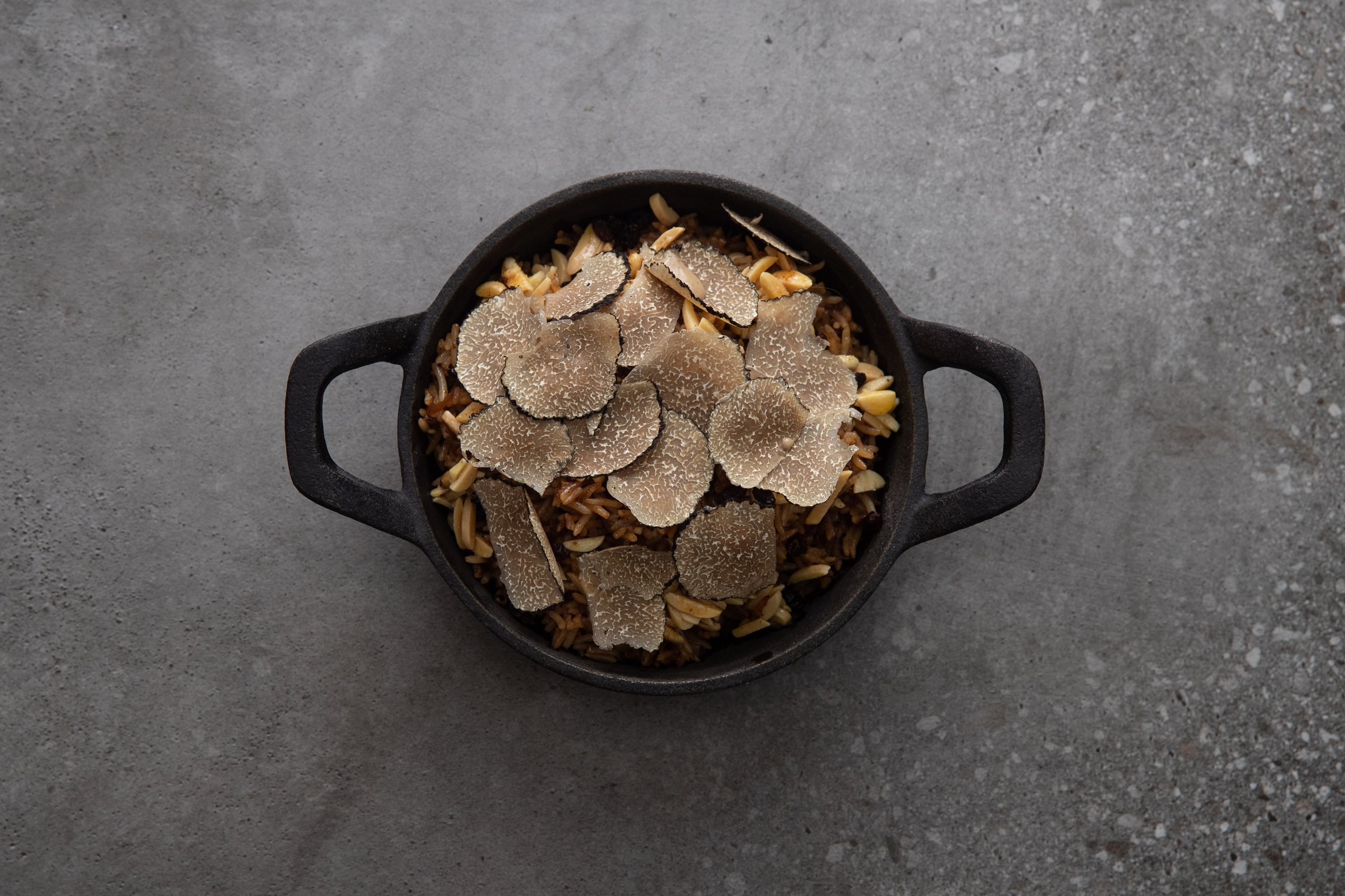 NOUR Restaurant Sydney promotional material for truffle season featuring truffle shavings on a bed of seasoned rice served on a skillet