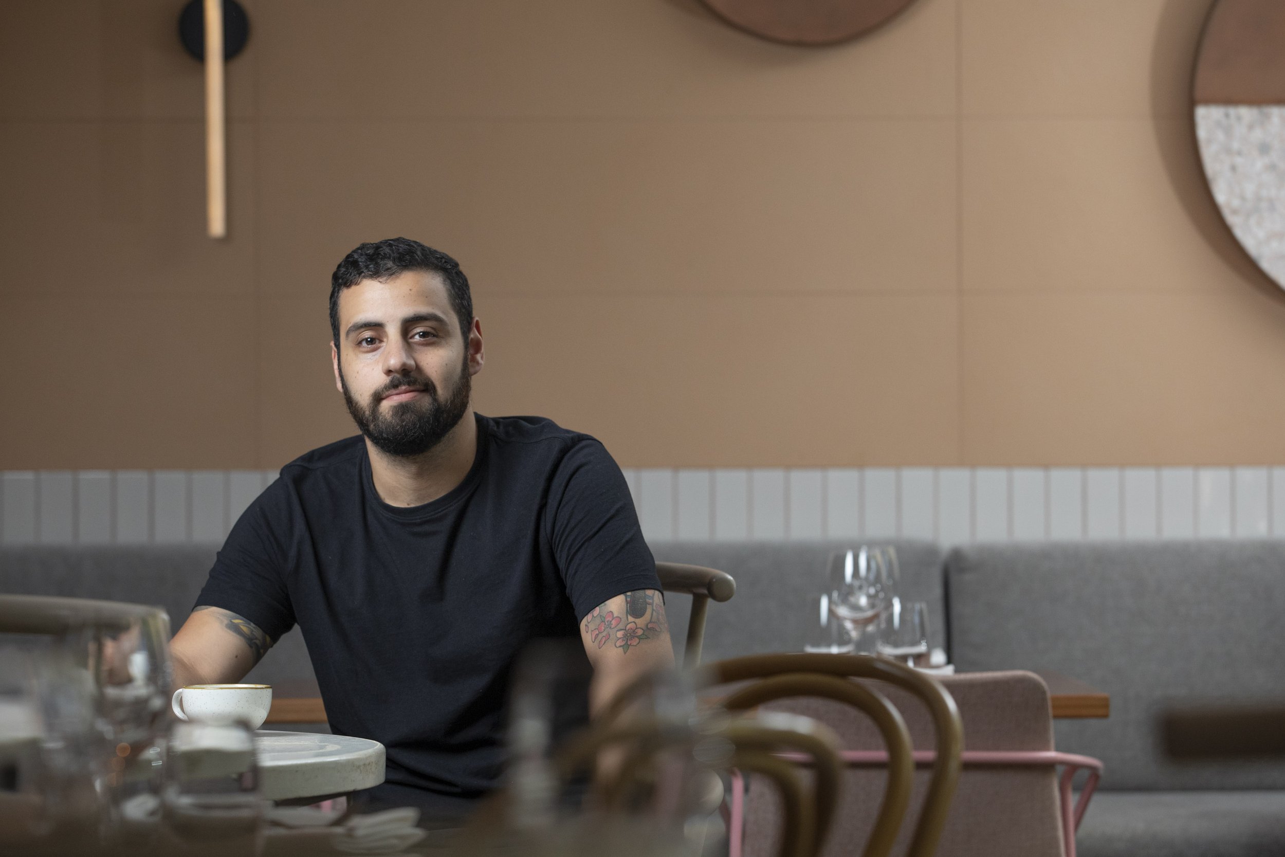 NOUR Restaurant Executive Chef Paul Farag in a relaxed pose at NOUR Restaurant, set against the backdrop of the dining area